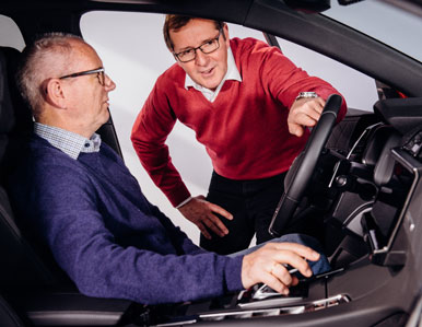Zwei Personen sitzen in einem Fahrzeug und führen ein Gespräch